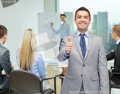 Image of happy businessman in suit showing thumbs up