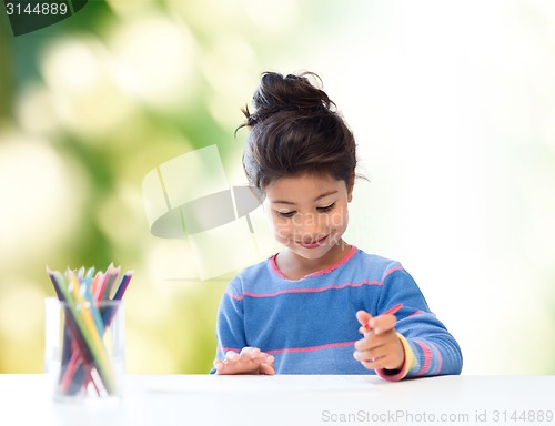 Image of happy little girl drawing with coloring pencils