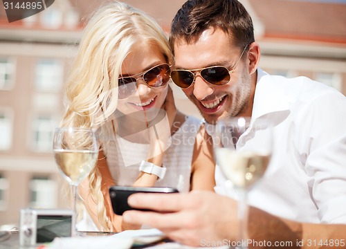 Image of couple looking at smartphone in cafe