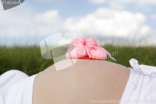 Image of Pregnant woman with pink baby shoes on her belly