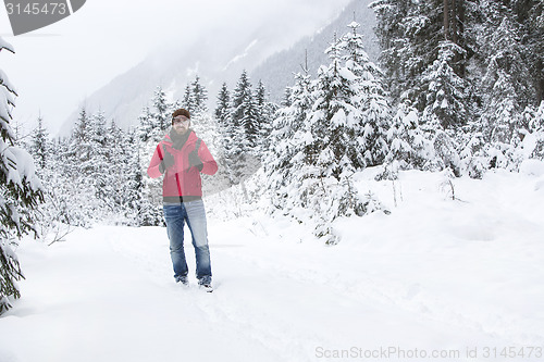 Image of Young man with snow glasses hiking in wintry forest landscape