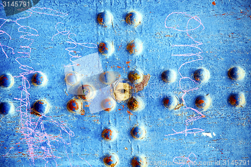 Image of pink paint in   blue wood door and rusty nail