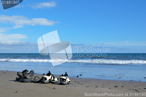 Image of Two pair of sandals at a beach