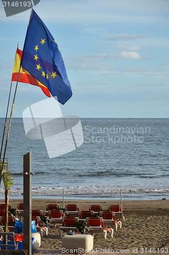 Image of Flags at the beach with sunbeds