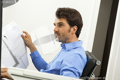 Image of Young man reading written agreements for work