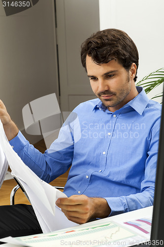 Image of Young man reading written agreements for work