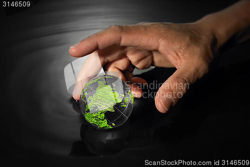 Image of Hand reaching for crystal earth ball