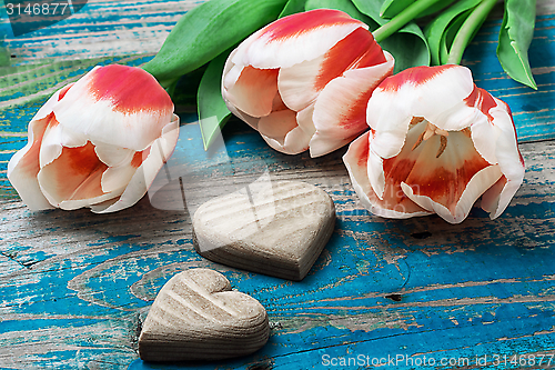 Image of three hand-carved wooden heart with bouquet tulips