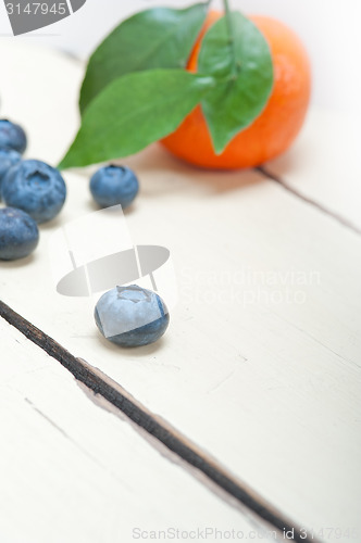 Image of tangerine and blueberry on white table