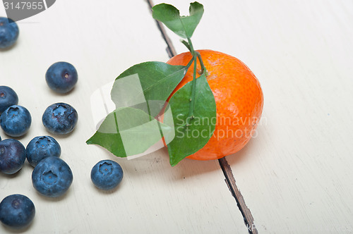 Image of tangerine and blueberry on white table
