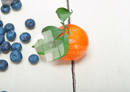 Image of tangerine and blueberry on white table