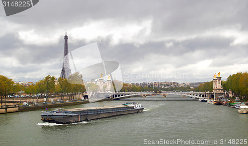 Image of Eiffel Tower on the bank of river Seine with ship spring cloudy day