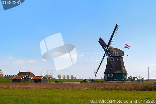 Image of Sunny Dutch landscape in springtime with green grass and an historic mill.