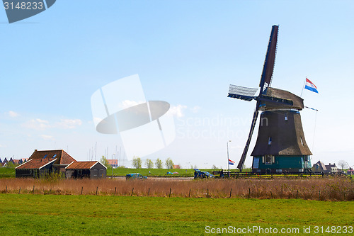 Image of Sunny Dutch landscape in springtime with green grass and an historic mill.