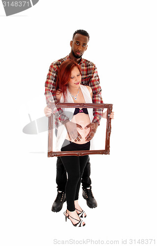 Image of Pregnant couple holding picture frame.