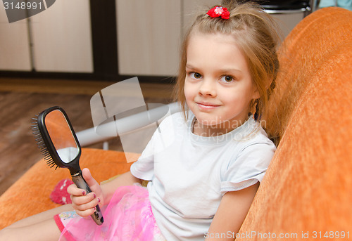 Image of Little girl with a mirror sits on the couch