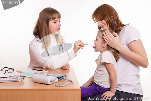 Image of Pediatrician looking into the throat of the child sitting on the lap of mother