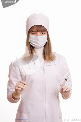 Image of Health worker in a white robe, mask, gloves with a syringe and vial in hands