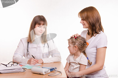 Image of Pediatrician listens to the complaints of the little girl and her mother