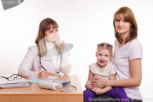 Image of Pediatrician, the child and his mother are sitting at the desk in the office