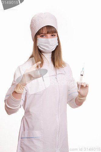 Image of Health worker in a mask with syringe and ampoule