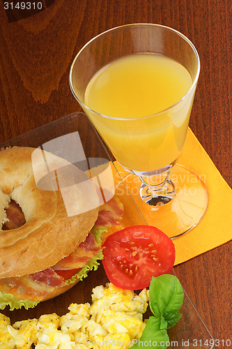 Image of Bacon and cheese bagel with scrambled eggs and juice