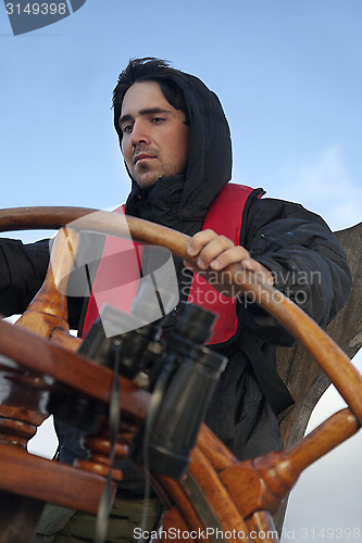 Image of Young sailor steering tall ship