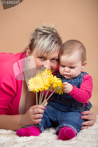 Image of infant baby with his mom and yellow flowers