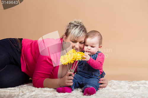 Image of infant baby with his mom and yellow flowers