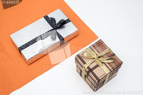 Image of brown and silver gift box with bow on white background