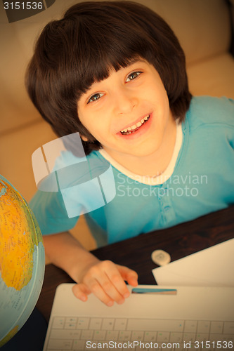 Image of smiling boy doing homework on computer