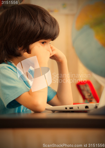 Image of pensive boy sitting at a table