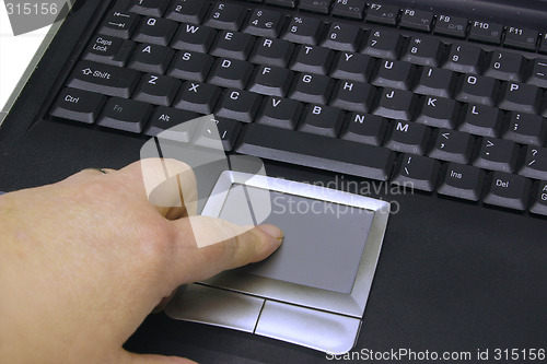 Image of finger on the mouse pad of a  laptop keyboard