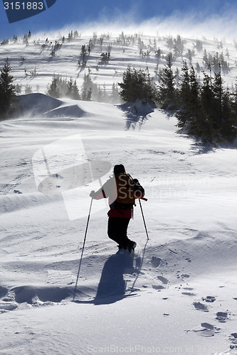 Image of Hiker in winter mountains at sunny windy day