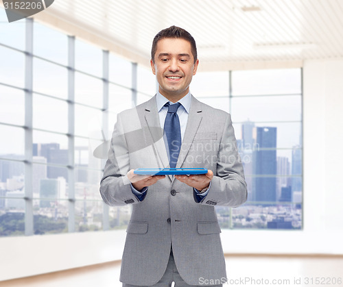 Image of happy businessman in suit holding tablet pc