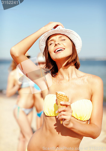 Image of girl in bikini eating ice cream on the beach