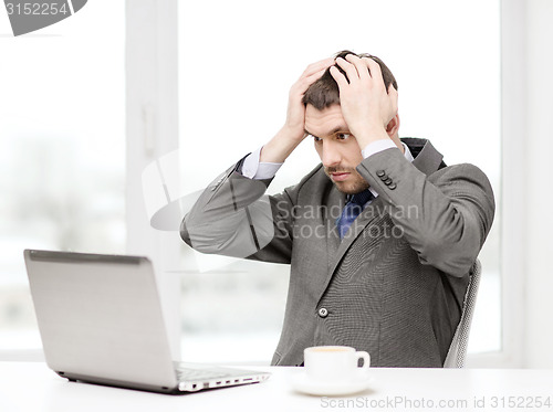 Image of busy businessman with laptop and coffee