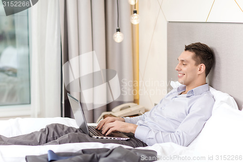 Image of happy businesswoman with laptop in hotel room