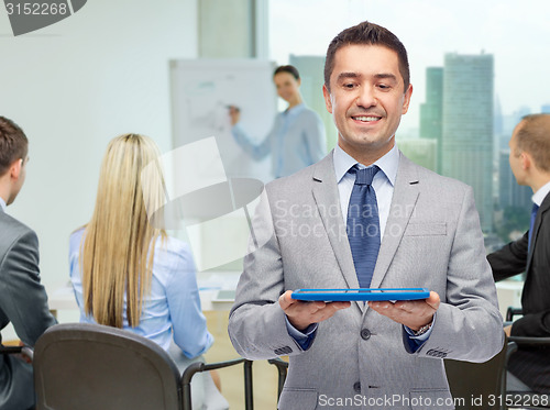 Image of happy businessman in suit holding tablet pc