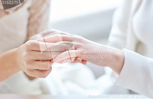 Image of close up of lesbian couple hands with wedding ring