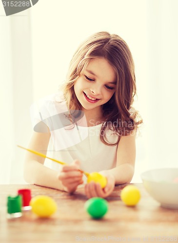 Image of smiling little girl coloring eggs for easter