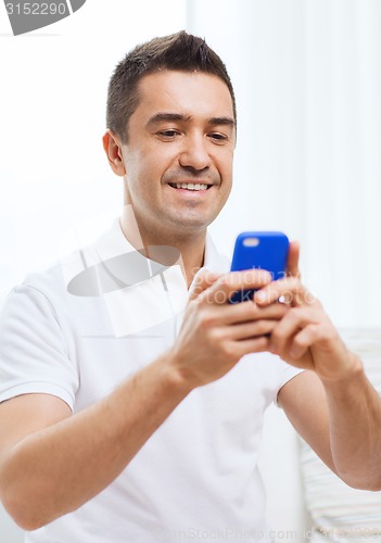 Image of happy man with smartphone at home