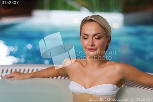 Image of happy womani sitting in jacuzzi at poolside