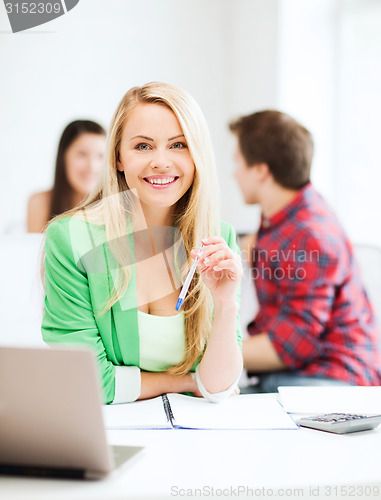 Image of smiling student girl with laptop at school