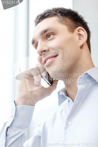 Image of smiling businessman with smartphone in office