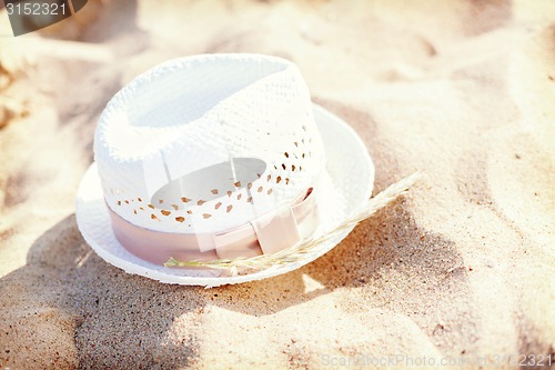 Image of white straw hat lying in the sand on the beach