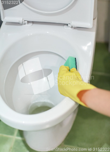 Image of close up of hand with detergent cleaning toilet