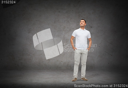 Image of smiling man with hands in pockets looking up