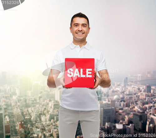 Image of smiling man with sale sigh up over city background