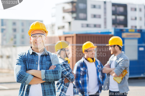 Image of group of smiling builders in hardhats outdoors